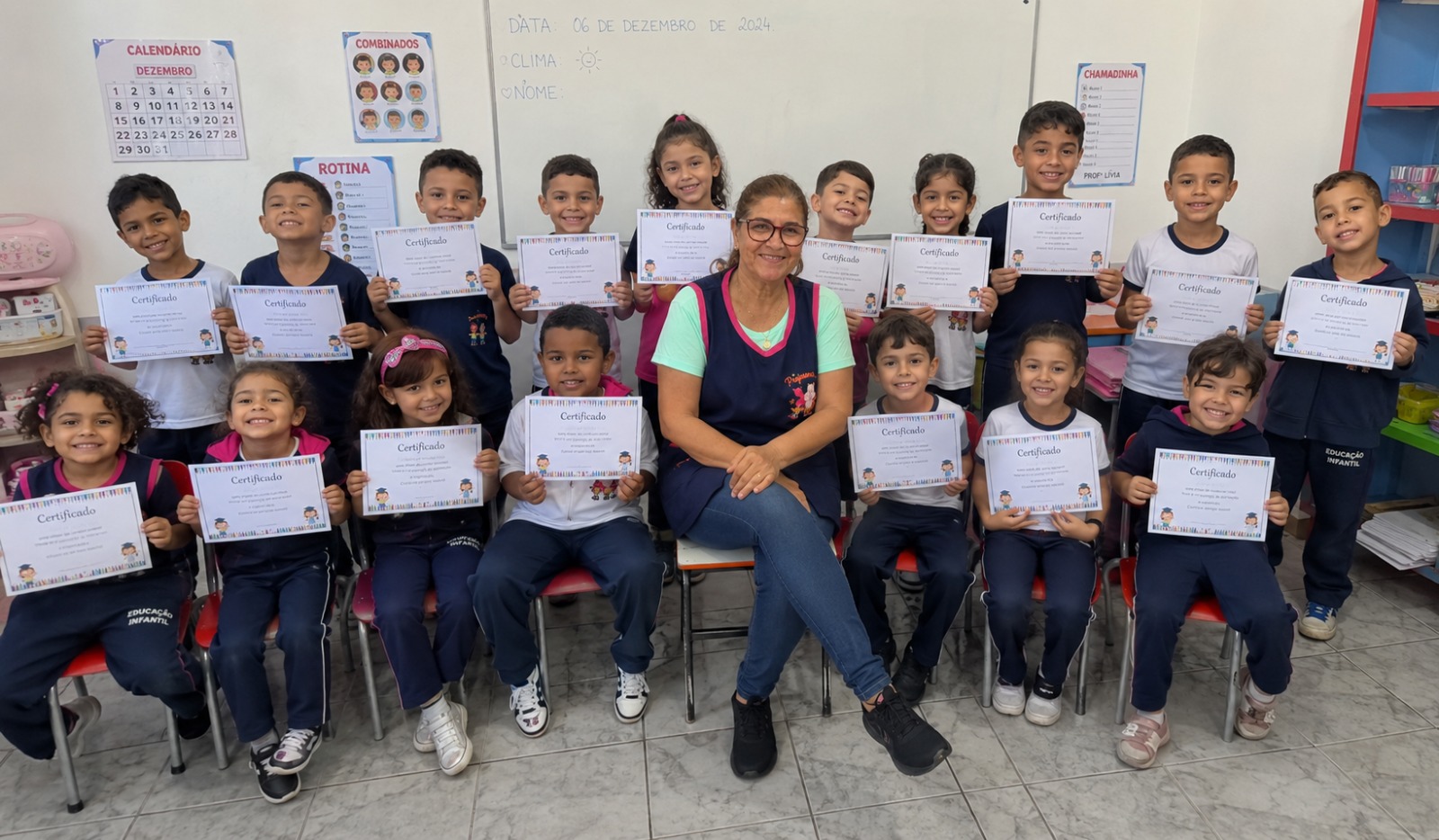 Professora e alunos da educação infantil segurando certificados em sala de aula